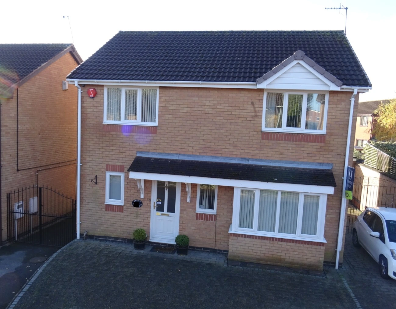 Front of a modern two-storey detached brick house with a tiled roof, canopy porch and block-paved driveway